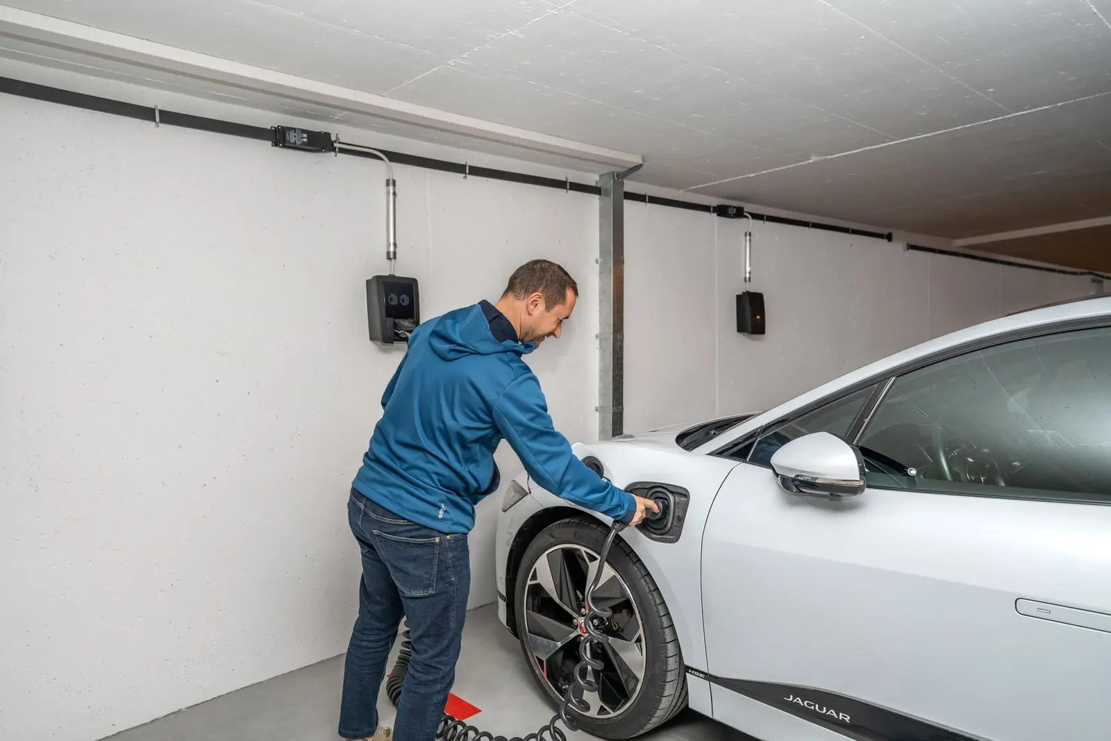 A man plugging an electric car into a charger in his garage
