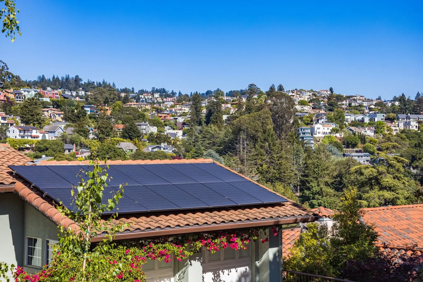 Solar panels on a tiled roof above a hillside neighbourhood