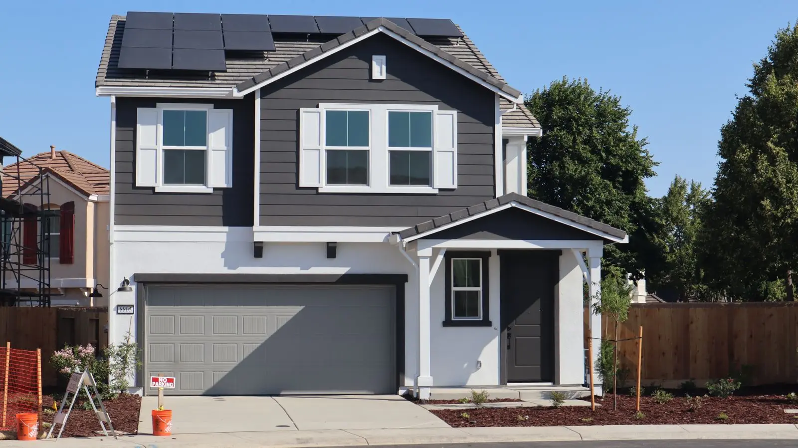 A two-storey suburban house with a row of black solar panels on its roof