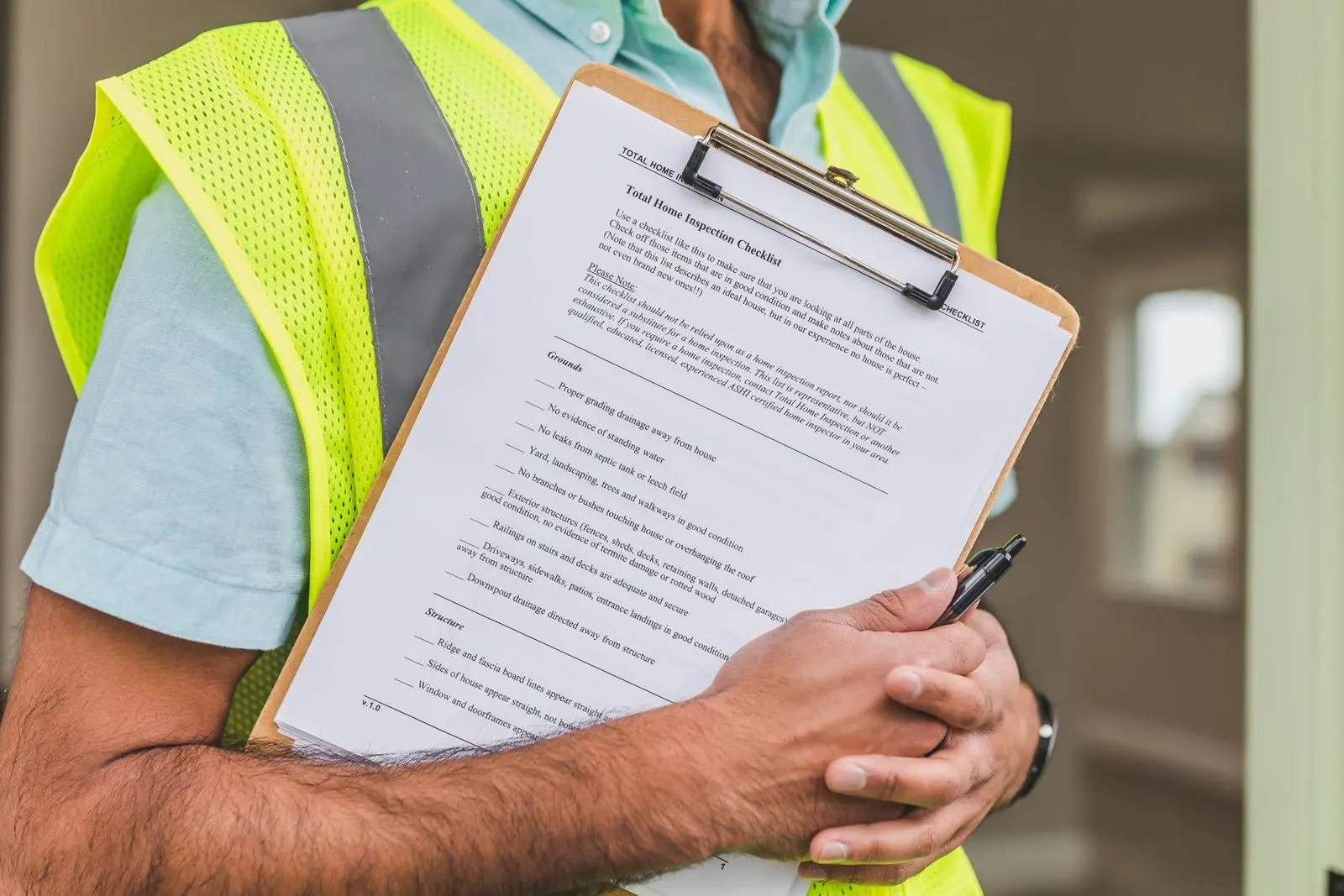 An inspector in a safety vest holding a house inspection checklist