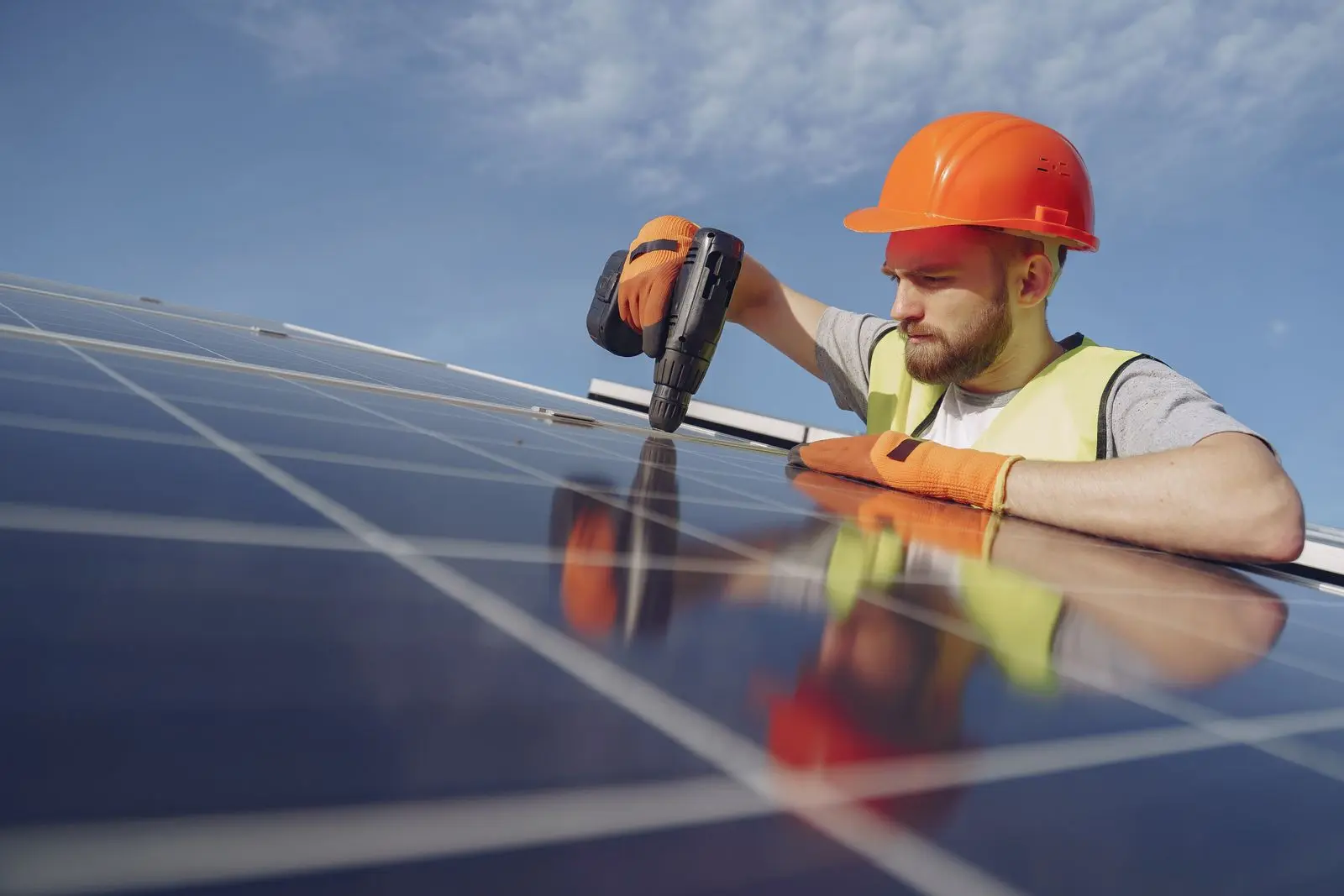 An installer in a hard hat fastening a solar panel