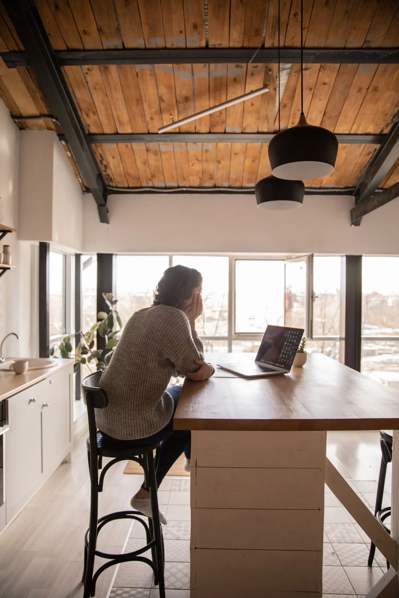 A woman researching on a laptop at her kitchen table