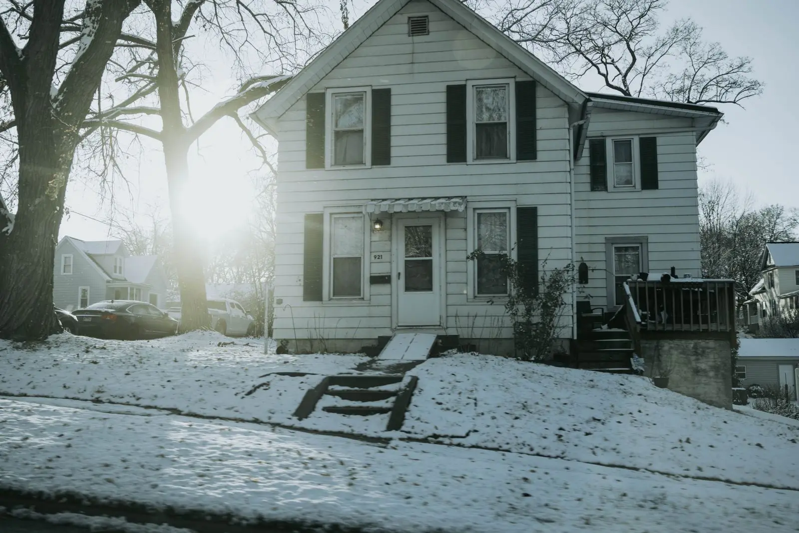 A white family house with snow on the ground in winter sun